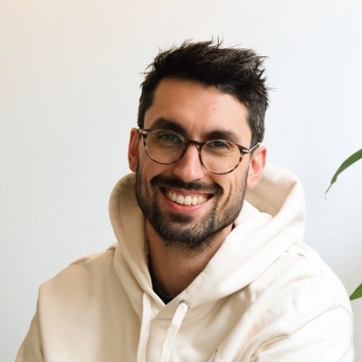 Joris, smiling, in glasses and a cream hoodie